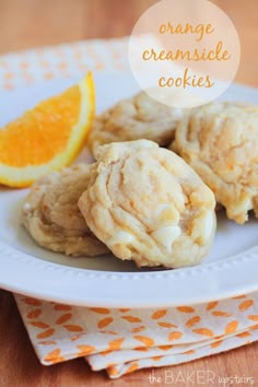 orange creamsice cookies on a white plate with an orange slice in the background