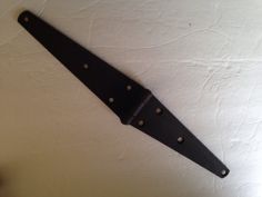 a black leather belt hanging on the wall with rivets and holes in it