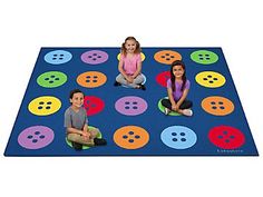 three children sitting on a blue rug with colorful buttons