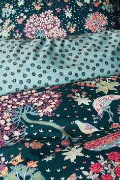 the bedding is covered with many colorful flowers and birds on black fabric, along with matching pillow cases