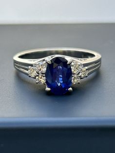 a ring with a blue stone surrounded by three white diamonds on top of a table