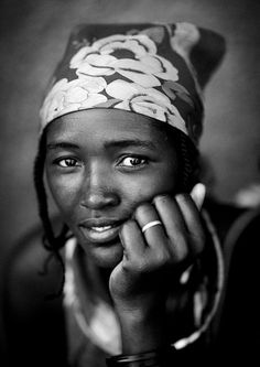 a black and white photo of a woman wearing a head scarf with flowers on it