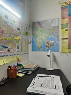 a desk with papers, pens and a lamp on it in front of a map