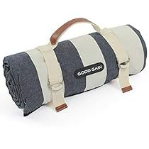 a large gray and white striped blanket on top of a wooden handle bag with straps