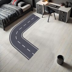 a room with a bed, desk and rug on the floor that is shaped like a road