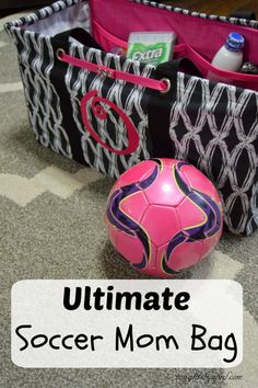 a pink soccer ball sitting next to a black and white bag with the words ultimate soccer mom bag on it