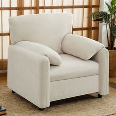 a living room chair with pillows on it in front of a rug and window sill