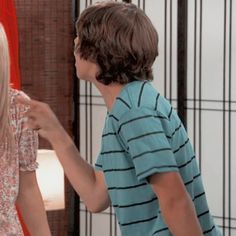 a boy and girl standing next to each other in front of a wall with red curtains