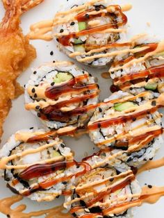 sushi rolls with sauce drizzled over them and garnished with vegetables