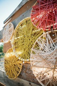 colorful string art hanging from the side of a wooden structure with red and yellow strings attached to it