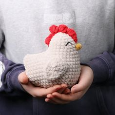 a person holding a small stuffed animal in their hands with a chicken on it's head