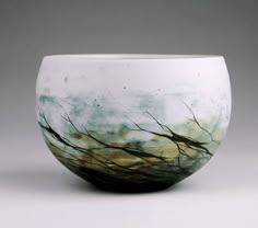 a white and black bowl with trees on it's side in front of a gray background