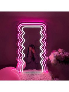 a woman taking a selfie in front of a mirror with neon lights on it