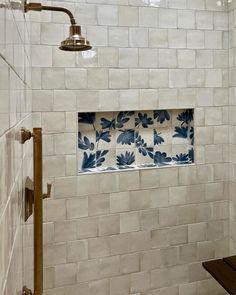 a white tiled shower with blue flowers on it