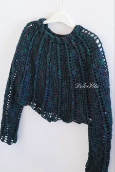 a crocheted sweater hanging on a hanger