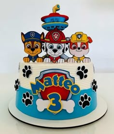 a birthday cake with paw patrol characters on it's top and paws around the base