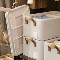 two suitcases are stacked on top of each other in a closet with clothes hanging from the wall