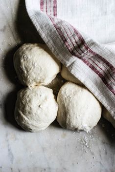 four uncooked doughnuts sitting on top of a table next to a towel