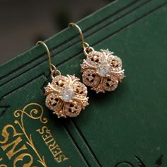 Beautifully sparkly 18k gold plated dangle and drop earrings in a Regency / Victorian style with perfectly shaped round faceted cubic zirconia stones. The drops measure 1.5cm (0.6") in length. Perfect wear for any occasion or to give as a special, thoughtful gift. Your earrings will arrive to you in gift box ready to give or to treat yourself. These earrings are perfect for a bride or bridesmaids for a classic or vintage themed wedding. If you would like a larger quantity, please DM us or email Vintage Dangle Earrings, Edwardian Earrings, Victorian Gold Earrings, Regency Jewelry, Earrings Zirconia, Victorian Style Earrings, Art Nouveau Earrings, Victorian Style Jewelry, Art Nouveau Earring