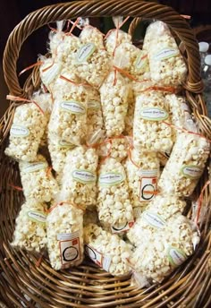 a wicker basket filled with lots of white chocolate covered popcorn bags sitting on top of each other