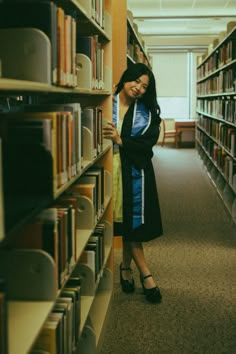 a woman standing next to a book shelf in a library