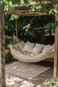 a white hammock hanging from a wooden pergolated area with pillows on it