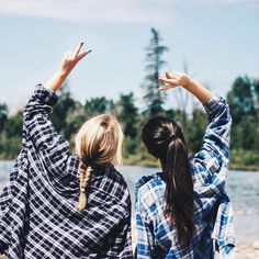 two women standing next to each other with their arms in the air