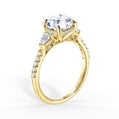 a yellow gold engagement ring with an oval center stone and side stones on the sides