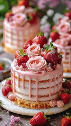 there is a cake with pink icing and strawberries on top, surrounded by other cakes