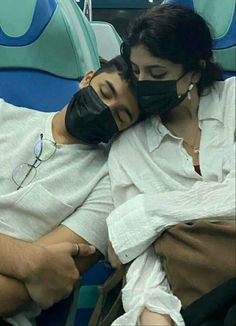 a man and woman wearing face masks while sitting next to each other