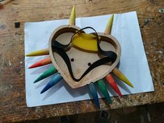 a heart shaped wooden object with multicolored sticks sticking out of it's sides