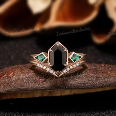 an emerald and diamond ring sitting on top of a piece of wood