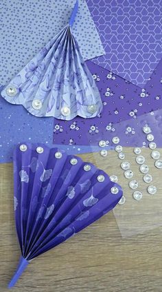 purple and white paper with silver sequins next to a fan on a wooden table