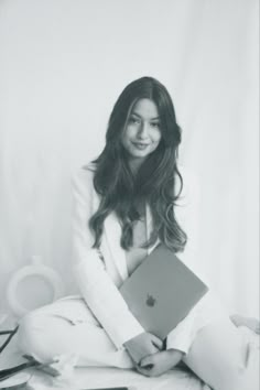 a black and white photo of a woman holding an apple laptop