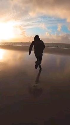 a man running on the beach at sunset with his feet in the water and one foot in the sand