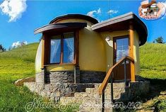 a small round house sitting on top of a lush green hillside