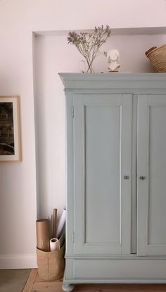 a blue armoire sitting on top of a hard wood floor next to a wall