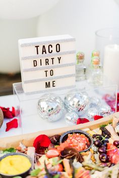 a table topped with lots of food next to a sign that says taco dirty to me