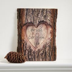 a heart carved into the bark of a tree with words written on it next to a pine cone