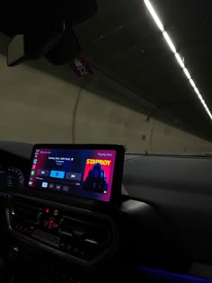 the dashboard of a car with an electronic device on it's display screen in a dark tunnel