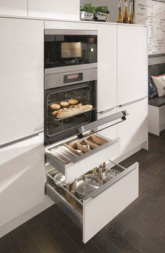 an open drawer in the middle of a kitchen that has food inside and on top of it