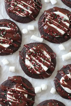 chocolate cookies decorated with marshmallows and sprinkles on white paper