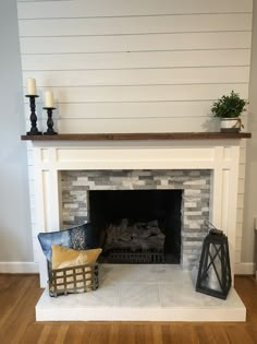 a white fireplace with two candles and a basket on the mantle in front of it