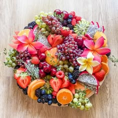 a bowl filled with fruit and flowers on top of a wooden table