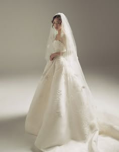 a woman in a wedding dress posing for the camera with her veil draped over her head