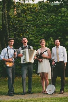 a group of people standing next to each other in front of trees and grass with an accordion