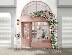 a pink store front decorated with flowers and greenery