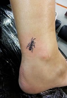 a small black spider tattoo on the ankle