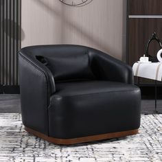 a black chair sitting on top of a rug in front of a wall mounted clock