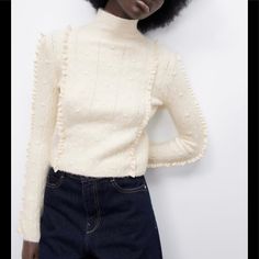 Size: S Color: Light Ecru Ref. 4331/136 High Collar Long Sleeve Sweater. Pompons And Lace Ruffle Detail. Main Fabric: 55% Acrylic. 4% Elastane. 28% Polyester. 13% Polyamide Lace: 100% Cotton Chic Long Sleeve Sweater With Ruffles, White Ruffled Sweater For Spring, Casual Cream Sweater With Ruffles, Chic Sweater With Ruffles For Layering, Feminine Textured Knit Winter Sweater, Chic Ruffled Sweater For Layering, Chic Fitted Sweater With Ruffles, Chic Cream Sweater, Cream Ruffled Sweater For Spring